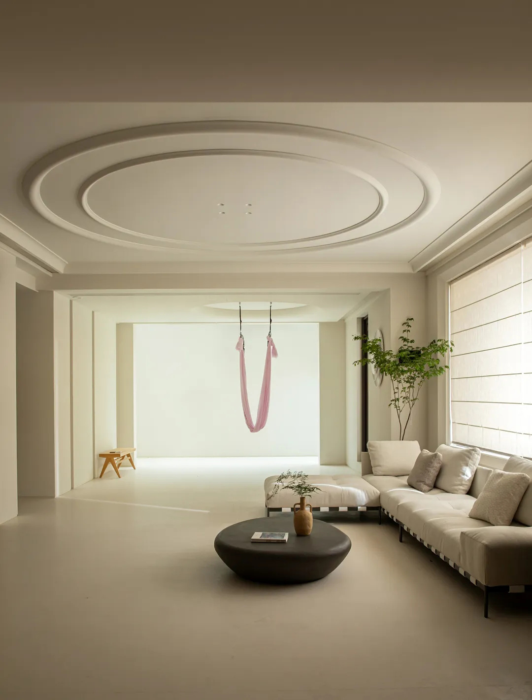 Soft minimalist living room with frameless white walls, flush ceiling, and a seamless concrete-toned surface throughout.
