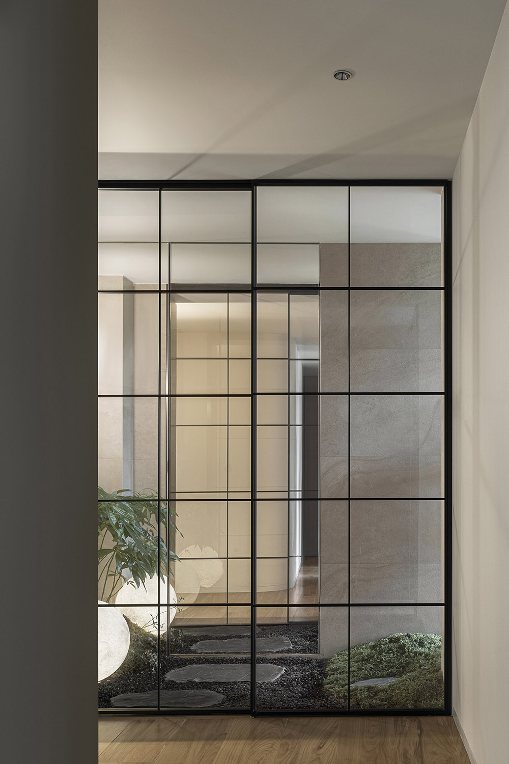 Minimalist interior with full-height glass panels and marble surfaces dividing spaces while maintaining visual openness.