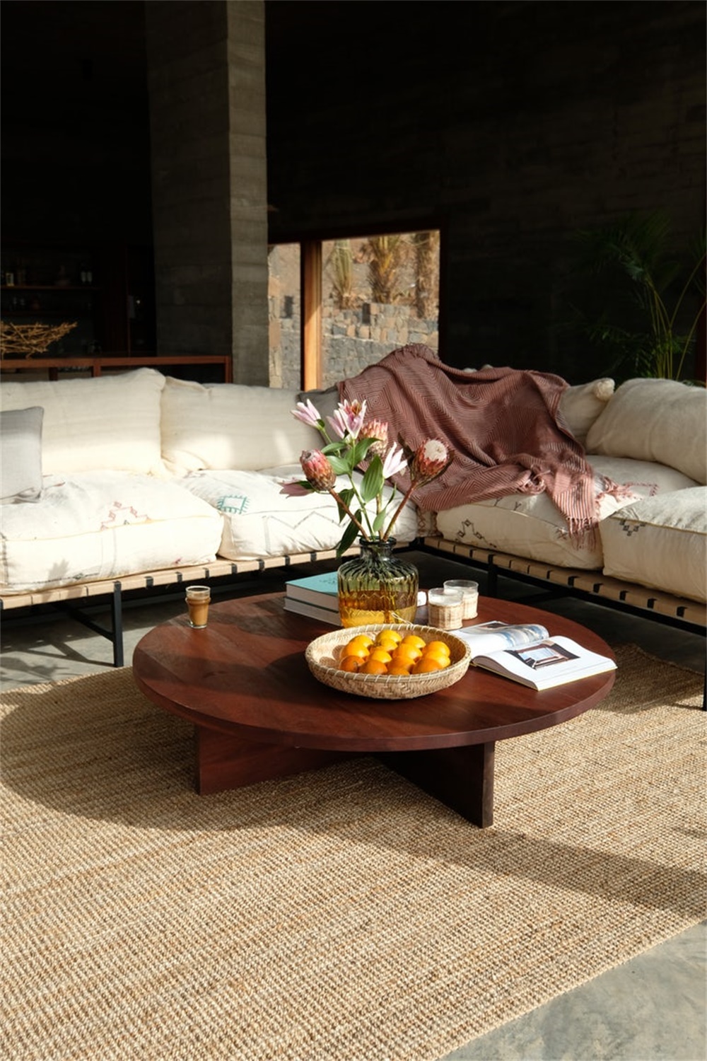 Modern living room with a round solid-wood coffee table, low seating, and warm ambient lighting.