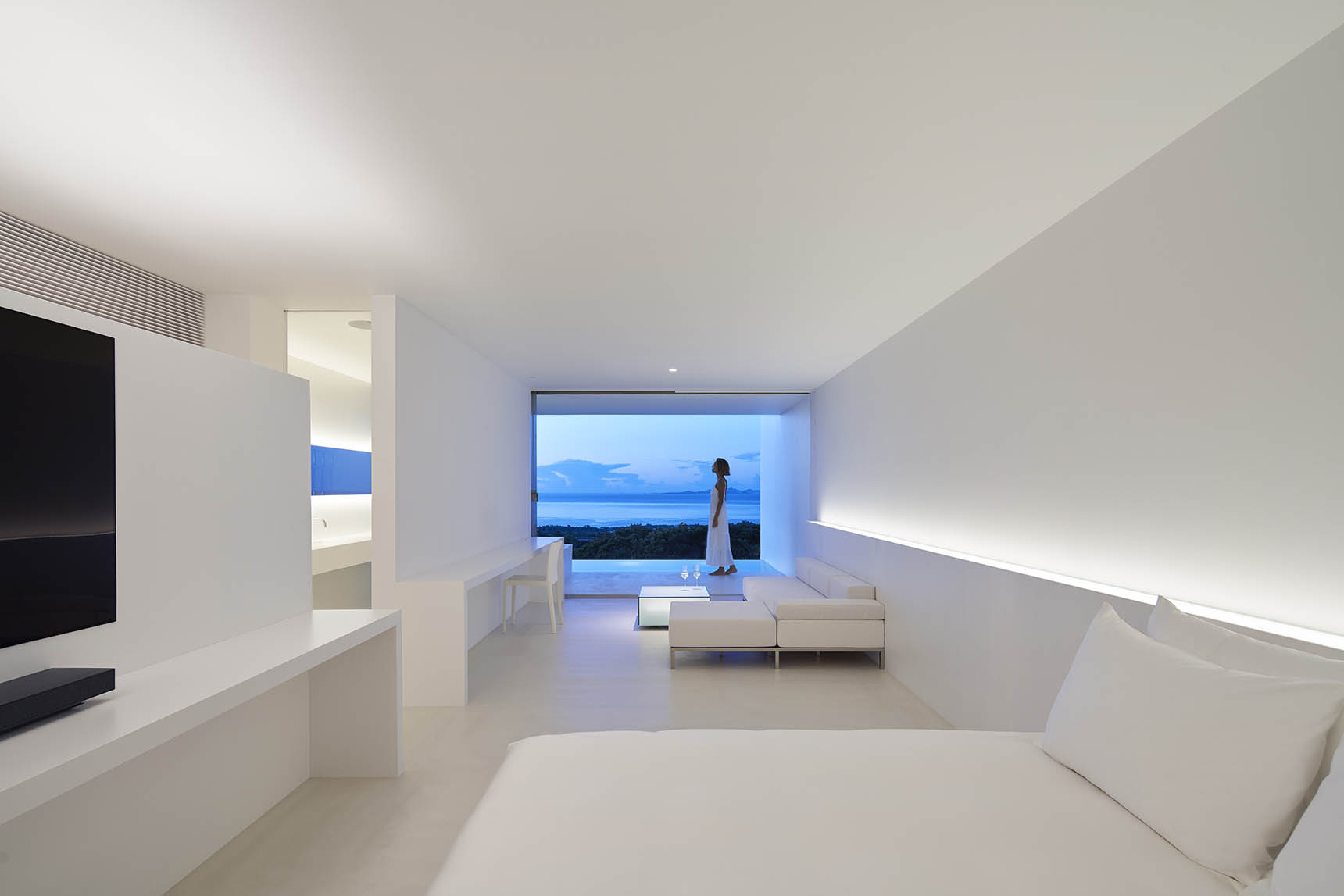 Minimalist residential interior with smooth plaster walls, warm neutral finishes, and no visible moldings or trim details.
