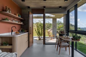 A modern kitchen with wooden finishes and a view of the outdoors through large windows.