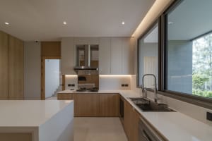 Modern residential kitchen with white countertops and wooden cabinets.