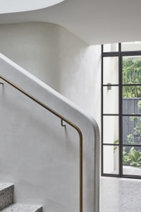 Industrial interior image showcasing concrete staircase with brass handrail.