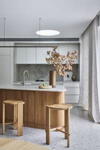 A modern kitchen featuring marble countertops and wood accents, with a minimalist design aesthetic.