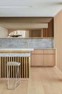 Modern minimalist kitchen featuring a stone countertop and wooden cabinets.
