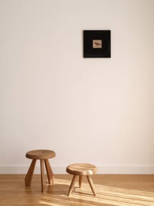 A minimalist wooden stool with three legs in a Scandinavian style setting.