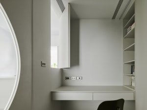 A modern minimalist home office with a floating desk, white walls, and a minimalist chair.