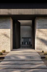 A modern entryway featuring brick and concrete materials, with an open door inviting into a light-filled interior.
