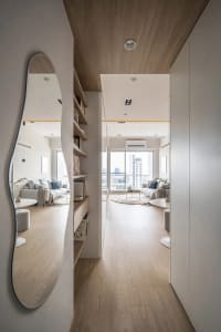 A modern living room featuring wooden flooring, minimalist furniture, and a balcony view.