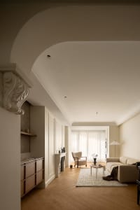 Minimalist living room featuring a white fireplace, beige armchair, and neutral color palette.