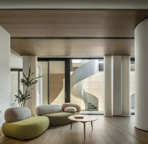 Minimalist living room with a green sofa, circular coffee table, and potted plant