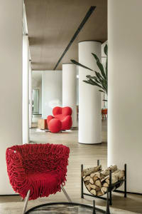 Modern interior design featuring wooden columns and a red knit-fabric covered chair.