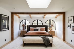 A minimalist bedroom features wood elements, round windows, and a skylight.