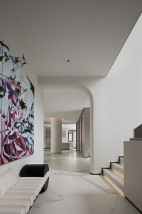 A modern living room featuring marble flooring and a large abstract painting on the wall.