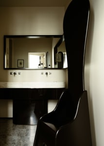 A minimalist bathroom with a marble countertop, black vanity, and a large mirror above it.