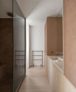 Modern minimalist bathroom featuring concrete and wood materials, including a walk-in shower, sink, and towel rack.