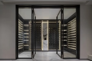 An industrial-style wine cellar with illuminated glass shelves and a central display area.