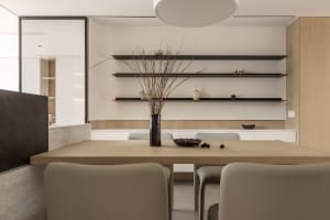 A modern dining room with white walls, wooden table, and minimalist shelves.