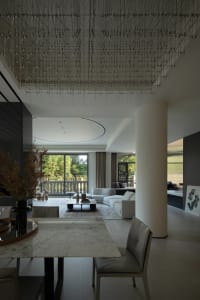 Minimalist modern living room with white marble table, glass chandelier, and leather furniture, featuring large windows and o