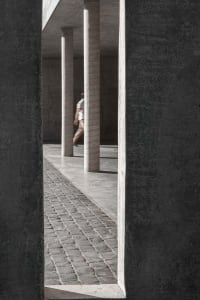 A minimalist concrete pathway with tall white columns on a grey concrete background.
