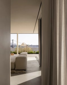 A modern, minimalist living space with concrete walls and floor, a white sectional sofa, and a floor lamp.