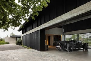Modern garage with black metal walls and concrete floor, featuring a classic car inside.