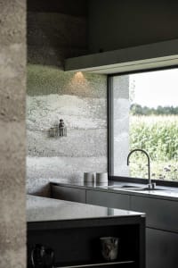 A modern kitchen featuring concrete walls and stainless steel appliances.