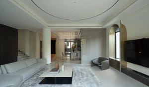 A modern living room with a minimalist design, featuring concrete walls, a white marble coffee table, and a ceiling light fix