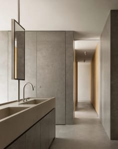 Modern minimalist bathroom featuring concrete tile flooring and walls, with a sleek faucet and minimalist design elements.