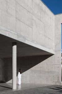 A modern architecture building made of concrete with a person standing in front.