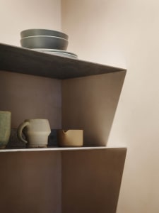 Concrete shelf with ceramic mugs and bowls.