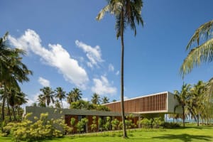 A modern house with a concrete exterior and palm trees surrounding it. Perfect for a tropical beach vacation.