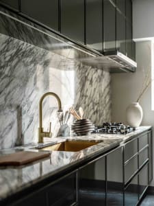 Modern kitchen with black cabinetry and marble countertops and backsplash.