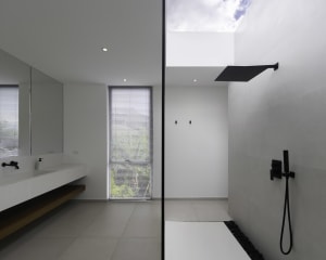 Modern bathroom with concrete walls and floor, minimalist design, and skylight