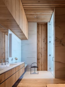 The modern bathroom features a minimalist design with marble walls and wooden accents.