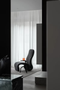 Modern living room with a black fabric chair and a lit candle on a small table.