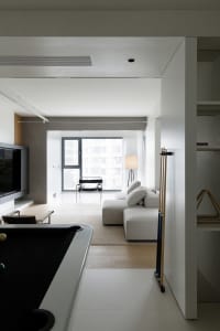 Minimalist living room with concrete walls, wooden floor, and fabric sofa.