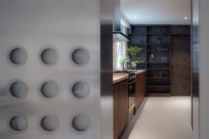 Modern kitchen featuring industrial-style metal shelves with round cutouts, wooden cabinets, and glass elements.