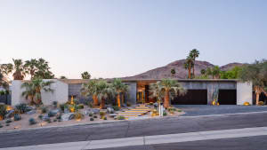 A modern house with a concrete exterior and palm trees in front of it.