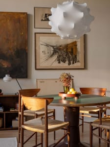 An industrial-style dining room features wooden furniture and a modern pendant light, with framed artwork on the wall.