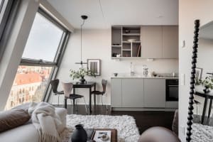 A modern, minimalist residential kitchen with white cabinets, a small dining table, and a sink