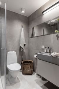 Modern bathroom with minimalist design, featuring concrete walls and floor, a floating vanity, and a walk-in shower.
