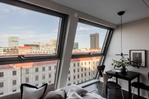 A modern living room featuring glass window frames with a cityscape view.