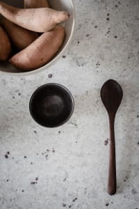 A simple food prep space with a wooden spoon and bowl placing on a textured surface.