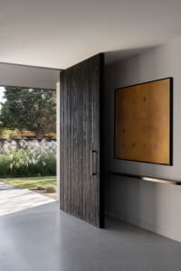 Modern industrial-style front door with a concrete base and wooden paneling in a residential entrance.