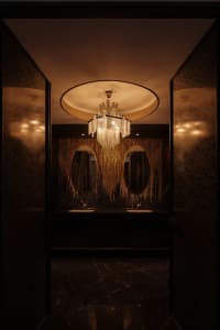 Interior of a modern bathroom featuring a luxurious chandelier and marble finishes.