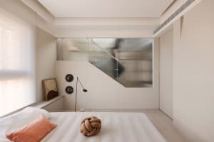 Minimalist bedroom featuring a bed with fabric bedding and a knotted decorative pillow.