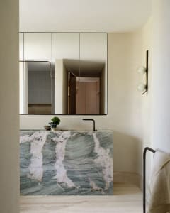 A modern marble bathroom featuring sleek lines, a black faucet, and minimalist design.