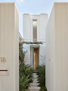 A minimalist house with a white brick facade and tall window.