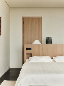 Minimalist bedroom featuring a wooden bed with a wooden headboard and white bedding.